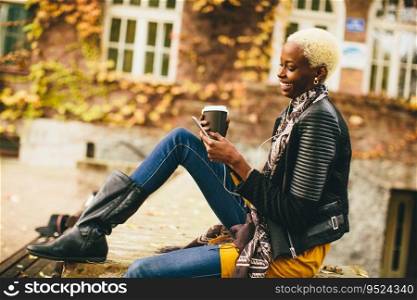 Pretty young black woman with mobile phone and coffee cup