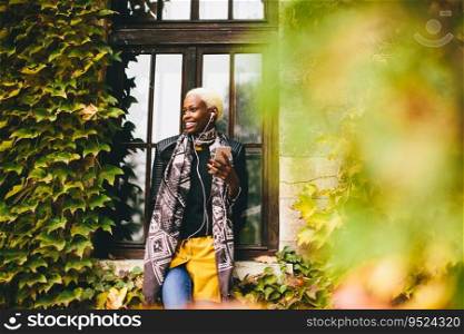 Pretty young black woman with mobile phone in the autumn park
