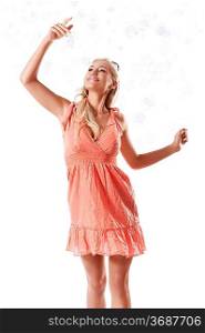 pretty young blond woman wearing a summer orange dress playing with some soap bubbles against white background