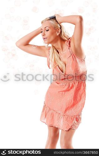 pretty young blond woman wearing a summer orange dress standing against white background playing with some soap bubbles