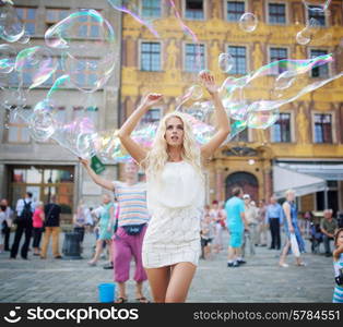 Pretty young blonde among lots of soap bubbles