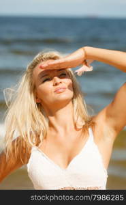 Pretty young blonde pretty girl at beach covering eyes. Woman have active time in summer. Summertime carefree concept.
