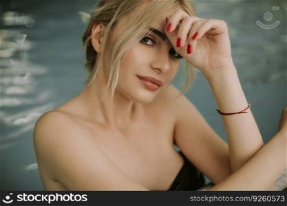 Pretty young blonde woman relaxing on the poolside