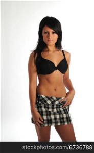 Pretty young brunette in black bra and plaid skirt