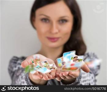 Pretty young brunette woman smiling with hands cupped together, sharing her photo and video files in social media resources. Virtual interface of future concept.