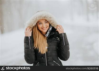 Pretty young brunette woman with hood on a snowy winter day