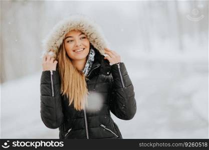 Pretty young brunette woman with hood on a snowy winter day