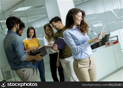 Pretty young business woman at startup office with digital tablet in front of her colleagues as team leader