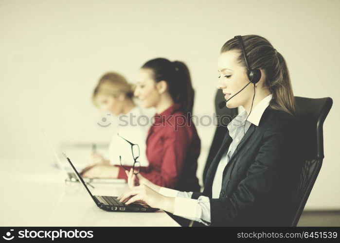 Pretty young business woman group with headphones smiling at you against white background