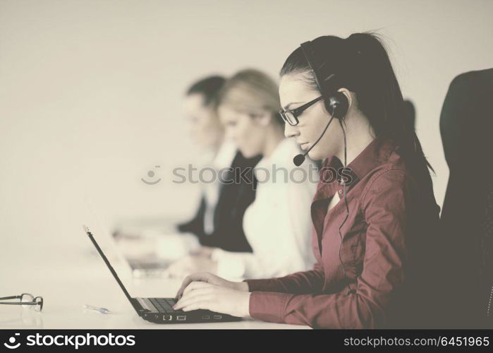 Pretty young business woman group with headphones smiling at you against white background