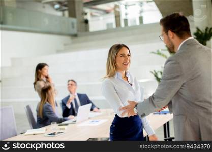 Pretty young business woman handshaking with his colleague in the office