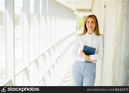 Pretty young business woman holding with notebook in the office hallway