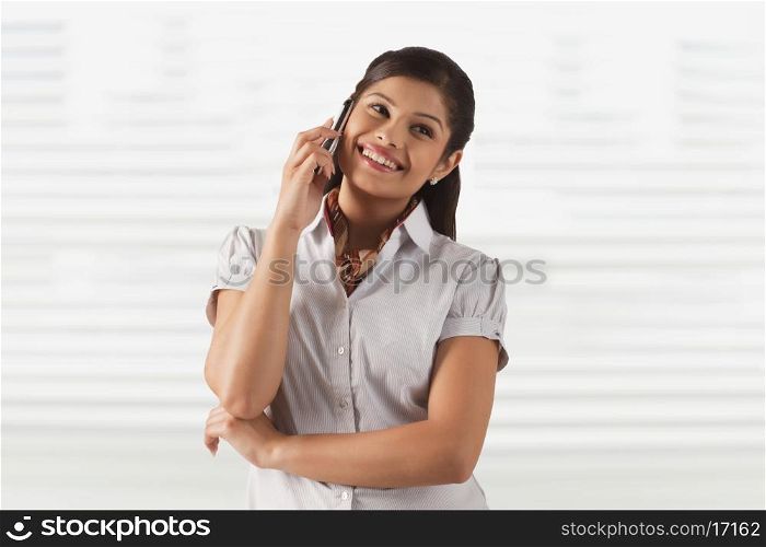 Pretty young business woman smiling while attending phone call
