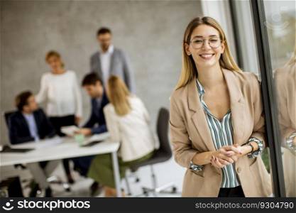 Pretty young business woman standing in the office in front of her team