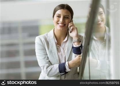 Pretty young business woman stands on the stairs at the modern office and use mobile phone