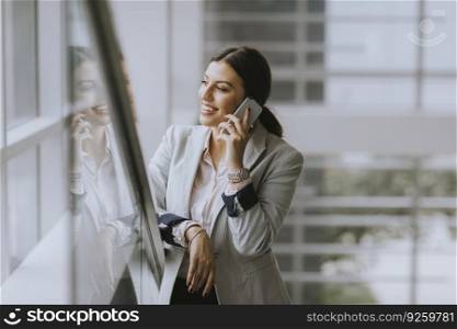 Pretty young business woman stands on the stairs at the office and use mobile phone