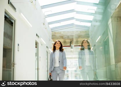 Pretty young business woman walking with briefcase in office hallway