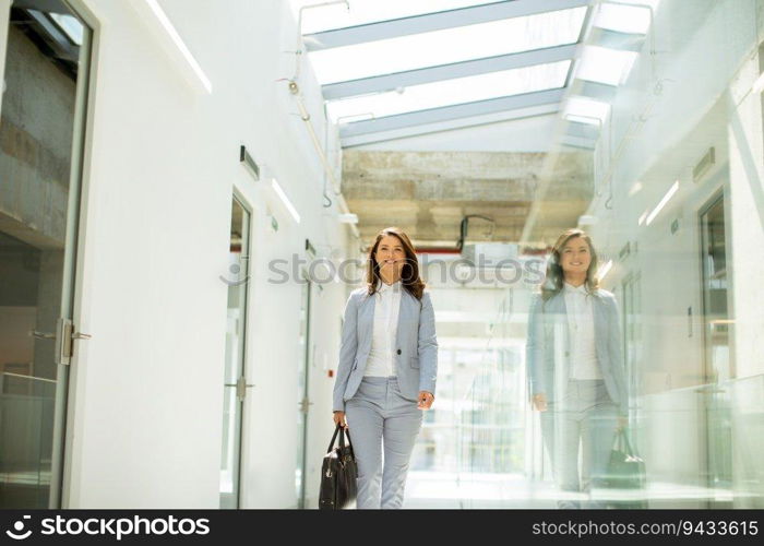Pretty young business woman walking with briefcase in office hallway
