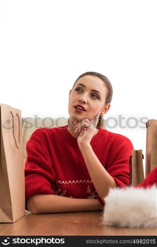Pretty young Christmas woman sitting at office with shopping bags and laughing