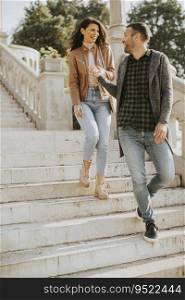 Pretty young couple smiling and talking while strolling down outdoor stairs on autumn day