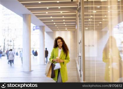 Pretty young curly hair woman with shopping bag and takeaway coffee cup in shopping