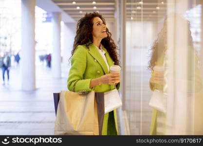 Pretty young curly hair woman with shopping bag and takeaway coffee cup in shopping