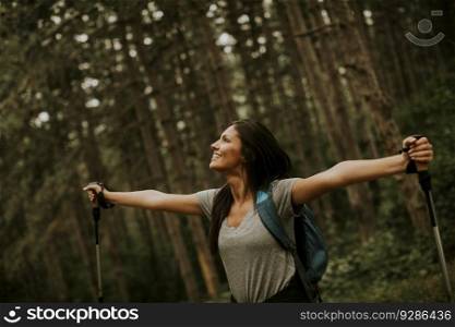 Pretty young female backpacker woman enjoying green beautiful forest around her