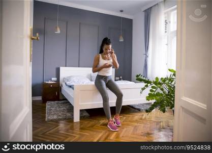 Pretty young fit woman choosing right musing for the exercises at home