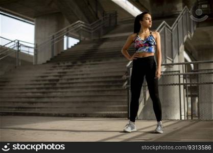 Pretty young fitness woman taking a break from running in urban environment