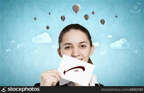 Pretty young girl holding white card with drawn smile. Your smile is your business card