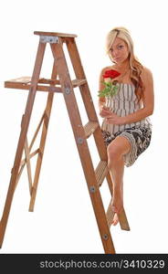 Pretty young girl in a black and white dress with long blondhair standing on the wooden stepladder, looking in the camera.