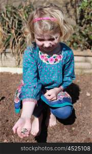 Pretty young girl showing sunflower seeds she is about to plant