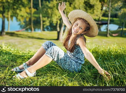 Pretty young girl sitiing on the fresh, green meadow