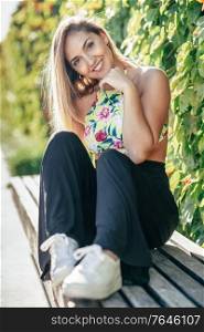 Pretty young girl sitting on urban bench outdoors. Pretty young girl sitting on urban bench