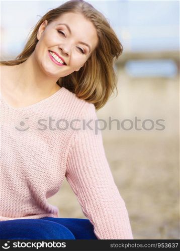 Pretty young girl walking on beach, relaxing wearing warm sweater during autumn weather.. Woman in sweater walking on beach