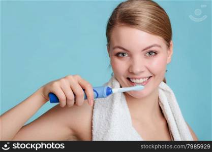 Pretty young girl with electric brush cleaning white teeth using toothpaste. Happy woman clean her oral cavity caring about dental health.. Young girl brushing oral cavity.