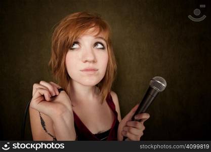 Pretty young girl with red hair on a green background with microphone
