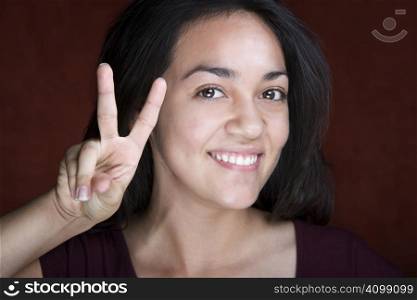 Pretty young Hispanic woman making peace sign