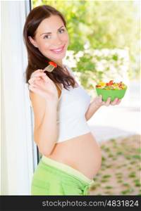 Pretty young lady expecting baby, new life, pregnant female eating tasty sweet fruit salad, happy motherhood concept