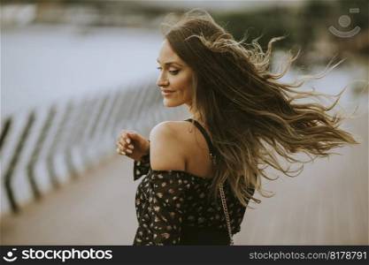 Pretty young long hair brunette woman walking on the riverside