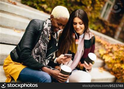 Pretty young multiethnic friends walking with coffee cups on autumn day