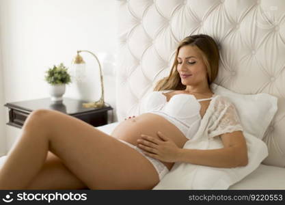Pretty young pregnant woman laying in the bed