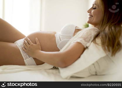 Pretty young pregnant woman laying in the bed