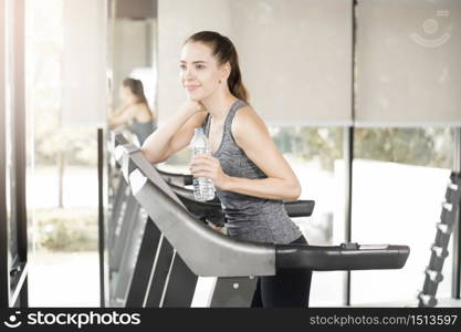 Pretty young sport woman is drinking water on treadmill in gym, Healthy lifestyle