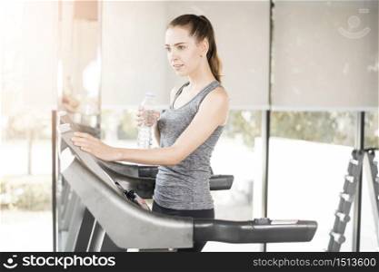 Pretty young sport woman is drinking water on treadmill in gym, Healthy lifestyle