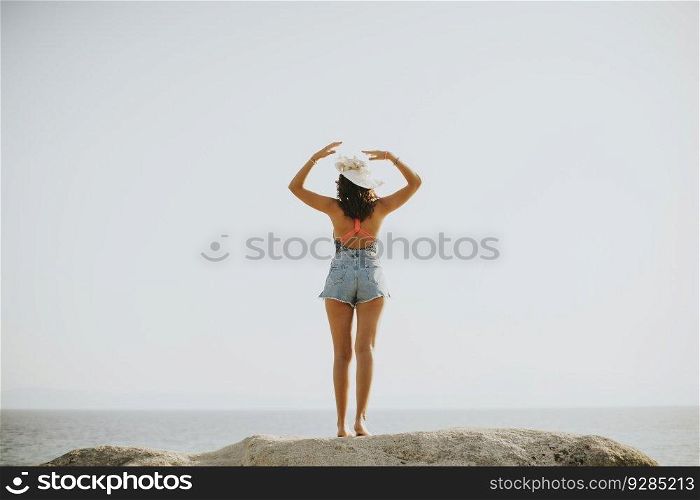 Pretty young woman at sea on the stony shore on a sunny day