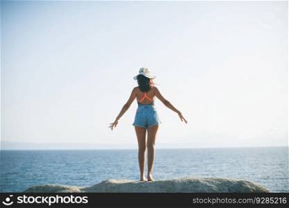 Pretty young woman at sea on the stony shore on a sunny day