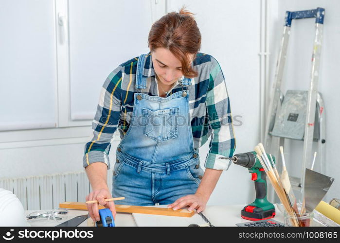 pretty young woman builder measuring a plank of wood