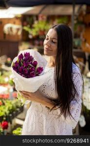 Pretty young woman buying flowers at the flower market
