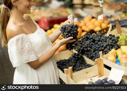 Pretty young woman buying fresh fruits on the market